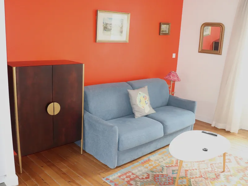 Sofa and antique wardrobe against the red living room wall of Le Carrousel