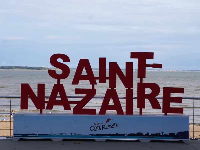 The red SAINT-NAZAIRE letters on the seafront promenade, with the beach and the estuary behind